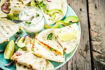 Mexican traditional food, quesadilla with chicken and vegetables, with white sauce, rustic wooden background copy space