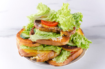 Stack of tasty toasts with vegetables on plate, white marble table