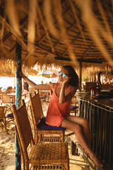 Obraz na płótnie Canvas Young woman wearing sunglasses sitting in the beach bar