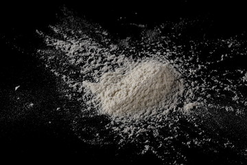 Wheat flour pile isolated on black background, powder texture