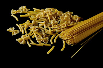 Spaghetti, farfalle noodles and macaroni, yellow pasta isolated on black background, clipping path
