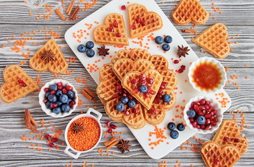 Fresh vegan waffles from red lentils. Healthy gluten-free pastries. Waffles, blueberries, pomegranate, red lentils on white Board
