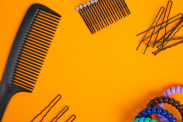 Hairbrush, barrette, hairpins and hair bands lies on orange background. Flat lay.