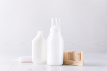 White plastic bottles with hair care products,wooden comb.Concept of hair treatments