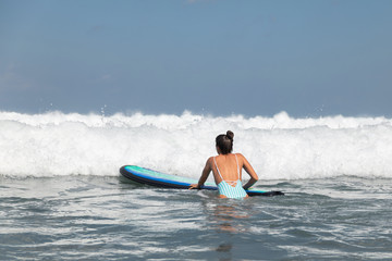 Woman surfer is trying to get into line up trough waves during her surfing workout