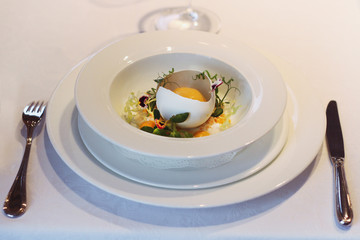 restaurant dish served on a white tablecloth. foie gras with lettuce in eggshell