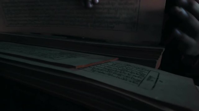 A person sorts through stacks of old manuscripts written in Nepali script.