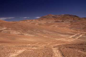 Wheel tracks in red barren waste landscape in the middle of nowhere of Atacama desert, Chile