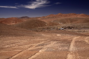 Wheel tracks in red barren waste landscape in the middle of nowhere of Atacama desert, Chile