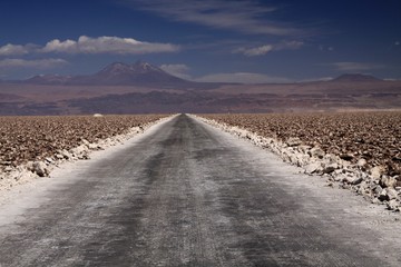 Endless dirt road with blurred horizon through salt flat 