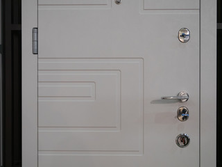 closeup of white entrance modern armored front door with few locks and handle