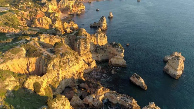 Algarve, Portugal. Flying over the coast of Atlantic ocean in the afternoon sun. Transparent turquoise ocean water. Aerial shot, 4K