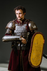 Medieval knight in armor holding sword and shield on the dark background