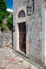 Ancient brick building in the fortress old bar, Montenegro. Antique wooden door and old lantern. Summer.