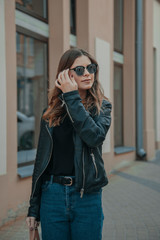 Fototapeta premium Happy girl with a Hollywood smile and glasses, walking in a park at sunset