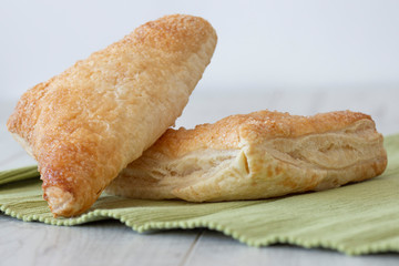 Apple turnover on a green tea towel with a grey wood background