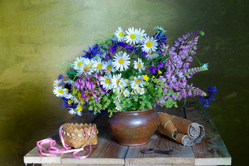 Bouquet with daisies and other flowers in a clay vase on a brown background