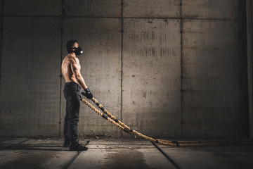 Muscular man doing battle ropes training