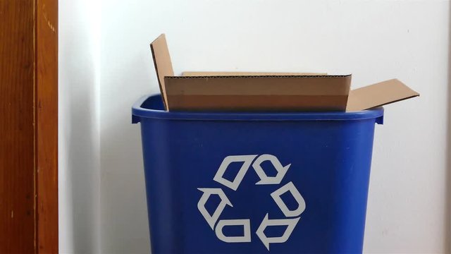A hand is adding shredded paper in the paper box to a recycling bin
