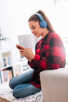 Girl listening to music. Woman at home with headphones.