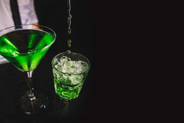 Green martini cocktail with fruit, black background. 