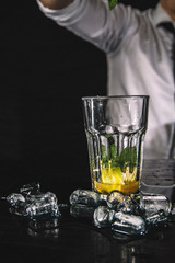 Bartender making a cocktail on a black counter. 