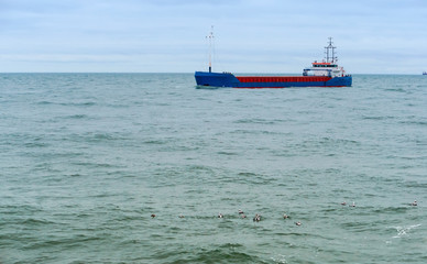 Cargo ship. Baltic sea. Empty container ship. Blue fishing boat. A small fishing boat.