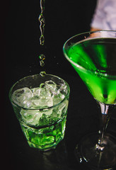 Green highball and martini cocktail on black bacground.