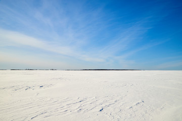 Fototapeta na wymiar Blue sky with white clouds over white snowy field in winter