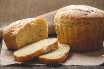 Homemade natural fresh bread with a Golden crust on a napkin on an old wooden background . Baking bakery products