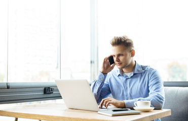 Stylish young man calling by the phone to solve business problems. Online consultation by phone. Freelancer discussing the development and planning of his online project. Outsourcing. Mobile services.