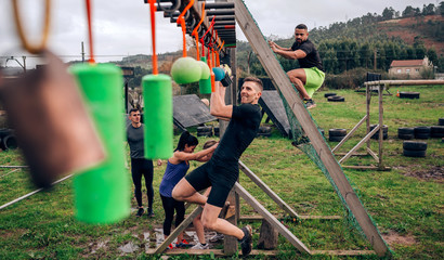 Male participant in an obstacle course doing suspension exercises
