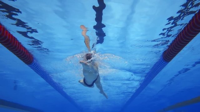 Muscular man under water in a swimming pool in super slow motion