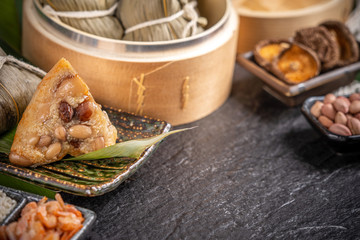 Close up, copy space, famous asian tasty handmade food in dragon boat(duan wu) festival, fresh from steamer steamed rice dumplings shaped pyramidal wrapped by leaves ingredients