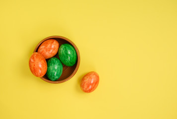 Easter eggs in ceramic bowl on yellow background.