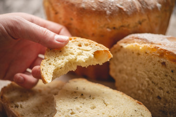Hands breaking homemade natural fresh bread with a Golden crust on old wooden background. Baking bakery products