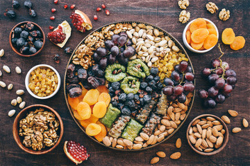 Middle East sweets, dry fruits and nuts on a copper tray. Top view, wooden background