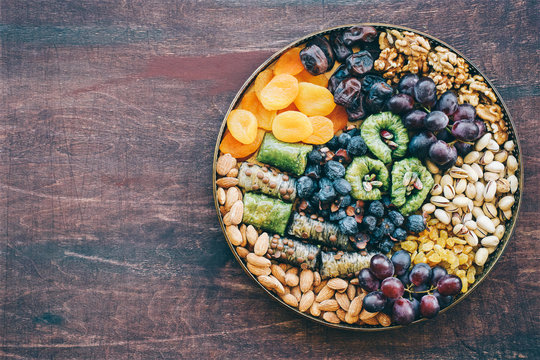 Middle East sweets, dry fruits and nuts on a copper tray. Top view, wooden background
