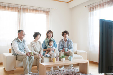 ソファに座りテレビを見る3世代家族