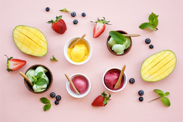 Ice cream set on a light pink background. Berry, pistachio, mango ice cream in bowls