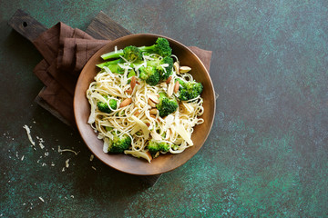 Spaghetti with broccoli and parmesan cheese. Dark green background