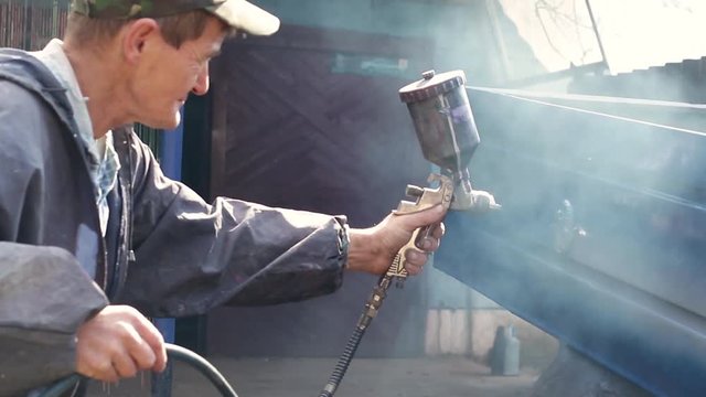 Worker Painting Blue Car Hindcarriage. Outdoors. Close-up, Blue Smoke, Dust.