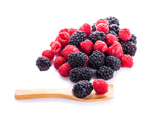 pile of raspberries and blackberries with leaves isolated on white background