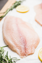 Raw tilapia fish fillet on the cutting board. Selective focus. Shallow depth of field.