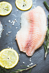 Raw tilapia fish fillet on the cutting board. Selective focus. Shallow depth of field.