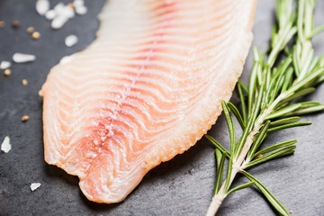 Raw tilapia fish fillet on the cutting board. Selective focus. Shallow depth of field.