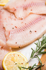 Raw tilapia fish fillet on the cutting board. Selective focus. Shallow depth of field.