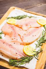 Raw tilapia fish fillet on the cutting board. Selective focus. Shallow depth of field.
