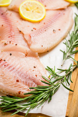 Raw tilapia fish fillet on the cutting board. Selective focus. Shallow depth of field.