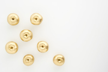 Obraz premium A group of seven gold painted metallic paint apples on a white background.